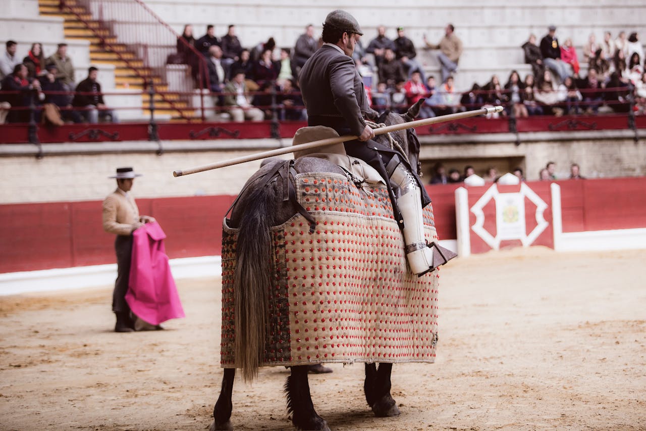 A picador on horseback with a lance prepares in a crowded bullring, showcasing traditional Spanish culture.