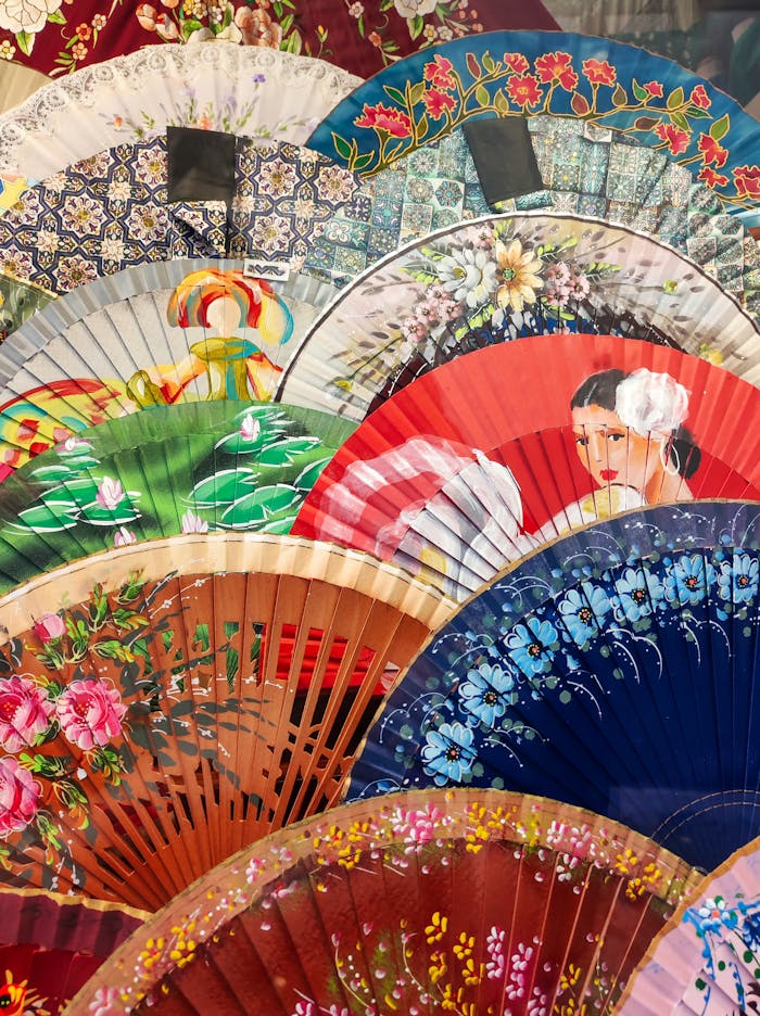 Vibrant Spanish hand fans with intricate designs and patterns displayed in an artistic arrangement.