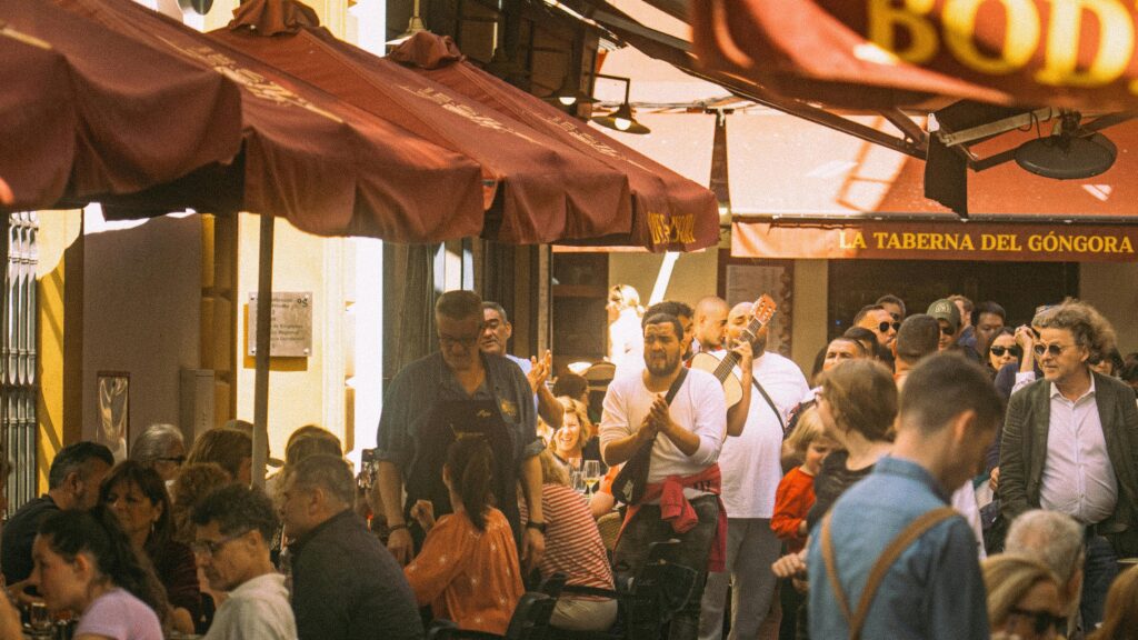 Bustling outdoor dining with musicians and lively crowd at La Taberna del Góngora, Seville.